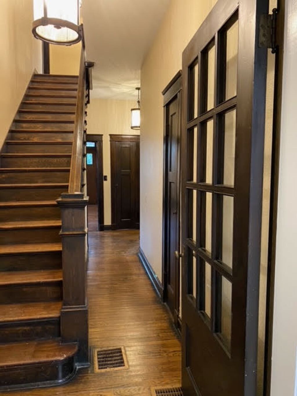 A wooden staircase with a handrail and a light fixture above it.