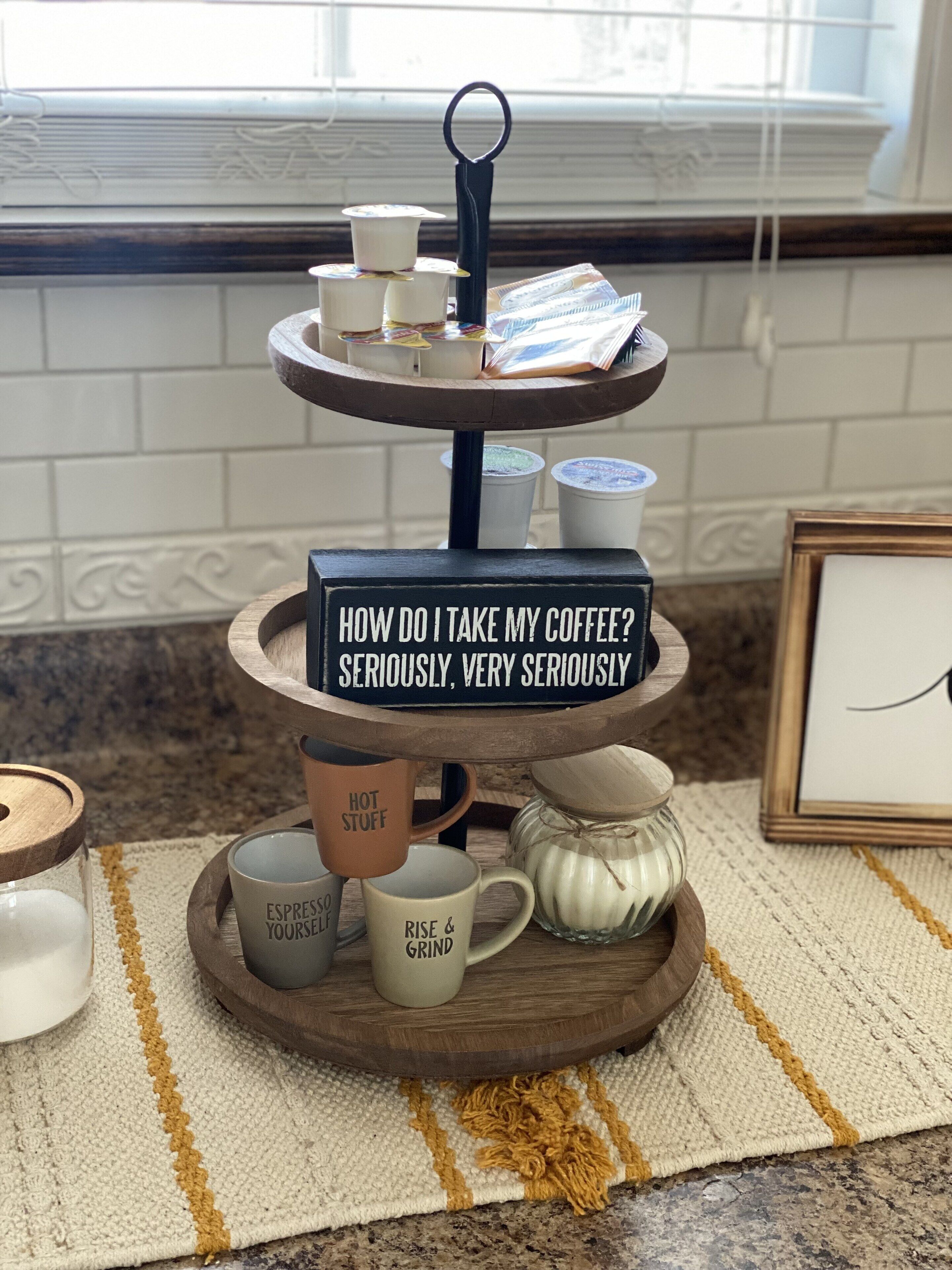 A tiered coffee stand with mugs and a sign.