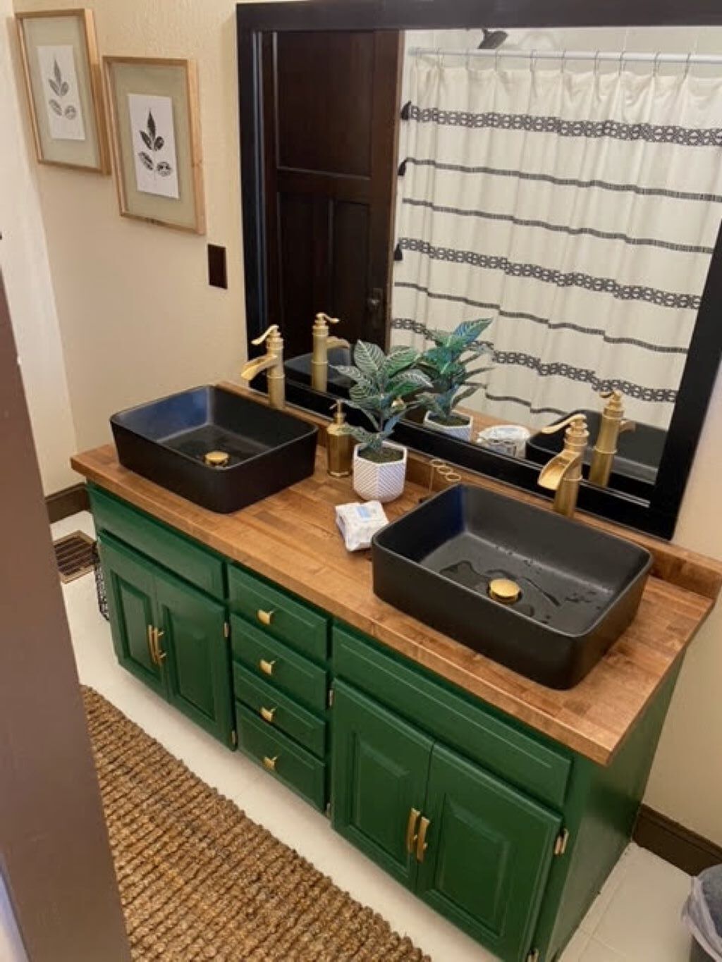 A bathroom with two sinks, green cabinets, and a mirror.