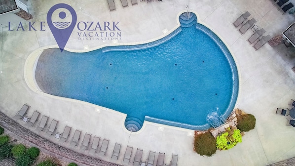 Vue aérienne d’une piscine avec des chaises longues et un panneau indiquant les destinations de vacances du lac Ozark.