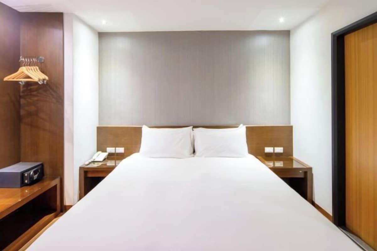 Ein Hotelzimmer mit einem großen Bett, einem Holz-Kopfteil, zwei Nachttischen mit Lampen, einem Nachttisch aus Holz und einem Holzschrank.