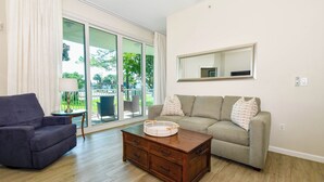 A living room with a sofa, a chair, a coffee table, and a sliding glass door leading to an outdoor area. - 1st Floor condo at The Palms of Destin with Free Beach Shuttle! (Destin)