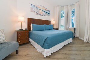 A bedroom with a large bed, two bedside tables with lamps, a nightstand, a dresser, and a window with curtains. - 1st Floor condo at The Palms of Destin with Free Beach Shuttle! (Destin)