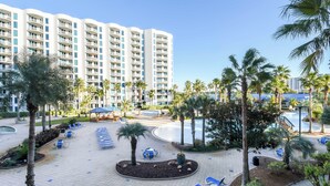 A resort with a pool area, palm trees, and a large building in the background.