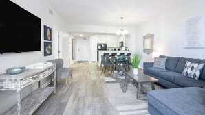 A modern living room with a sofa, coffee table, and a dining area with chairs and a table.