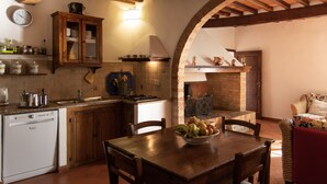 A kitchen with wooden cabinets, a stove, and a dining table with chairs. - Farmhouse in the greenery of the Tuscany countryside with private pool and view (Murlo)