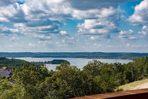 A lake surrounded by hills and trees, with a clear sky and clouds.