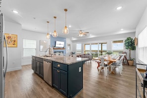 A spacious kitchen with a central island, pendant lighting, and a dining area with a view.