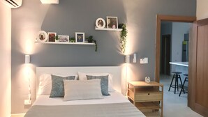 A neatly arranged bedroom with a large bed, bedside tables, a nightstand, and a small wooden desk with a chair. - A Estrenar con Piscina y gym en el Centro!! (Santo Domingo)