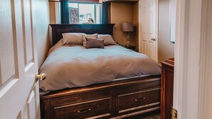 A neatly made bed with a headboard, a bedside lamp, and a wooden nightstand.