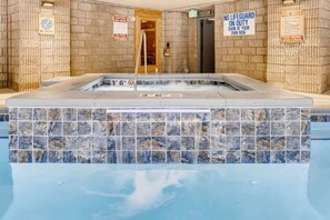 A hot tub with tiled walls and a sign indicating no lifeguard on duty.