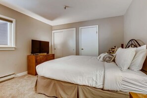 A bedroom with a large bed, a television on a wooden dresser, and two doors. - Lake Dillon! Ampitheatre, Walk to Lake,Pool&HT (Dillon)