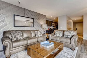 A modern living room with two leather sofas, a wooden coffee table, and a kitchen in the background. - Lake Dillon! Ampitheatre, Walk to Lake,Pool&HT (Dillon)