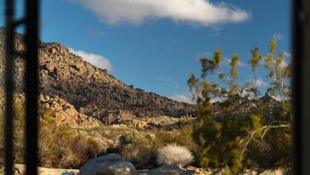 Un paysage montagneux, avec un ciel dégagé et une étendue d’eau qui reflète l’environnement.