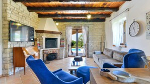Una sala de estar acogedora con chimenea de piedra, televisor de pantalla plana y asientos cómodos.