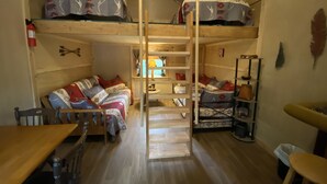 A cozy, compact room with bunk beds, a small dining table, and a wooden ladder. - Rustic Cabin (Bayfield)