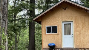 A small wooden cabin with a door and window, surrounded by trees. - Rustic Cabin (Bayfield)