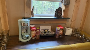 A wooden interior with a window, a shelf with various food items, and a bench. - Rustic Cabin (Bayfield)