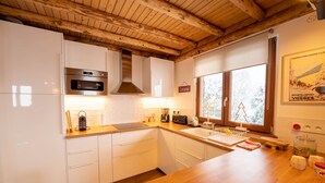 A modern kitchen with white cabinets, a stainless steel oven, and a wooden ceiling. - "Le Bois des Neiges" Charming authentic chalet  (Xonrupt-Longemer)