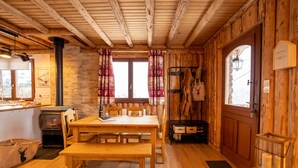 A cozy wooden cabin interior with a wooden table, benches, a fireplace, and a stone wall. - "Le Bois des Neiges" Charming authentic chalet  (Xonrupt-Longemer)