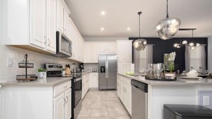 A modern kitchen with white cabinets, stainless steel appliances, and a central island.
