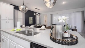 A modern kitchen with a large island, stainless steel appliances, and pendant lighting.