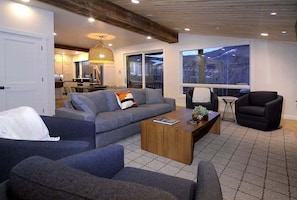 A modern living room with a sofa, armchairs, a coffee table, and a large window with a view.