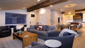 Ein modernes Wohnzimmer mit einer Couch, Sesseln, einem Couchtisch und einem Essbereich mit Stühlen und einem Tisch.