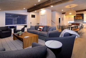 A modern living room with a sofa, armchairs, a coffee table, and a dining area with chairs and a table. - The Point (Mt. Crested Butte)