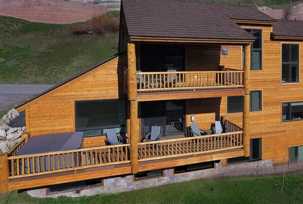 A two-story wooden cabin with a balcony, large windows, and a stone foundation. - The Point (Mt. Crested Butte)
