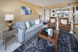 Ein Wohnzimmer mit einer Couch, zwei Sesseln, einem Couchtisch und einem Teppich.