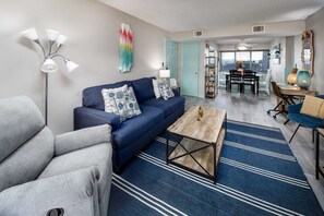 Ein modernes Wohnzimmer mit einem blauen Sofa, einem Couchtisch und einem Streifen Teppich.