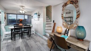 A modern kitchen with a dining area, a large mirror, and a staircase leading to another level. - Seaspray Condos - 104A (Fort Walton Beach)