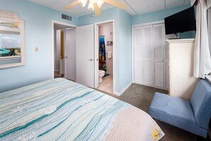 Une chambre à coucher avec un lit, une chaise, une télévision et une armoire.