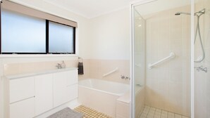 A modern bathroom with a bathtub, shower, and a glass-enclosed shower stall.