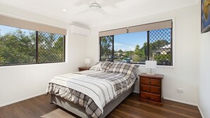 A bedroom with a large bed, two bedside tables, a nightstand, and a window with a view of the outside.