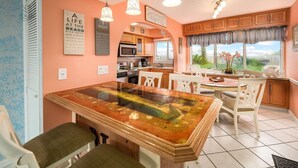 A kitchen with a dining table, chairs, and a view of the outdoors. - Seaspray Condos - 105B (Fort Walton Beach)