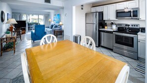 Una cocina moderna con electrodomésticos de acero inoxidable, un comedor con mesa de madera y una sala de estar con sofá azul.