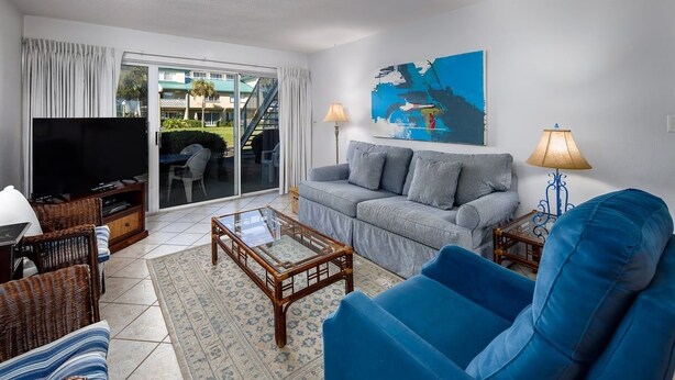 Una sala de estar con sofá, televisión y una mesa de centro de vidrio.