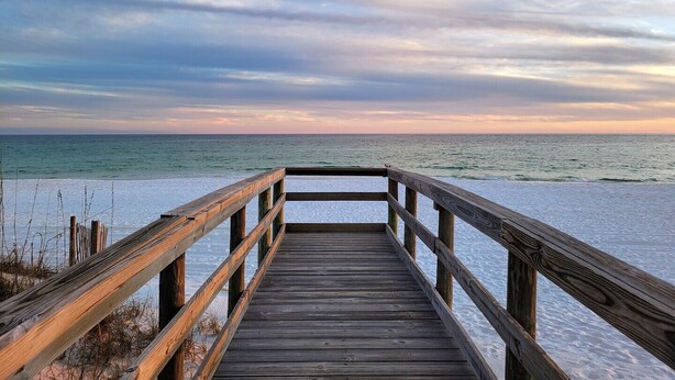 A wooden pier leading to a beach with a view of the ocean and a cloudy sky. - Seaspray Condos - 106D  (Fort Walton Beach)