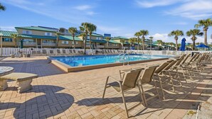 A pool area with lounge chairs and a pool, surrounded by buildings with a uniform architectural style.