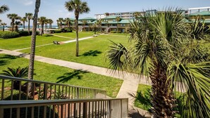 A hotel with a green lawn, palm trees, and a pool area.
