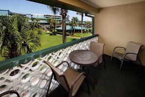 Ein Balkon mit Blick auf einen Hotelkomplex, der einen runden Tisch und zwei Stühle zeigt.
