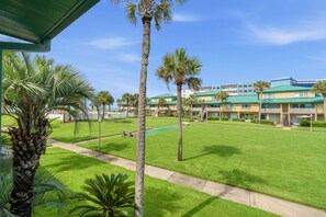 A hotel with a pool, palm trees, and a clear blue sky. - Seaspray Condos - 110D (Fort Walton Beach)