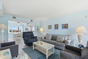 A living room with a sofa, armchairs, a coffee table, and a dining area with a table and chairs.