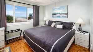 Une chambre avec un grand lit, une vue sur la plage et un tableau accroché au mur.