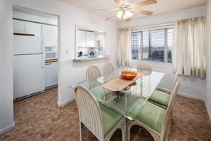 Un coin repas avec une table en verre, des chaises en osier et un ventilateur de plafond.