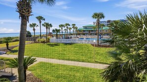 A resort with a pool, palm trees, and a view of the ocean. - Seaspray Condos - 115A (Fort Walton Beach)