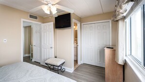 A bedroom with a bed, a television, and a door leading to a bathroom.