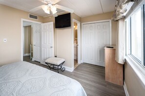 A bedroom with a bed, a television, and a door leading to a bathroom.